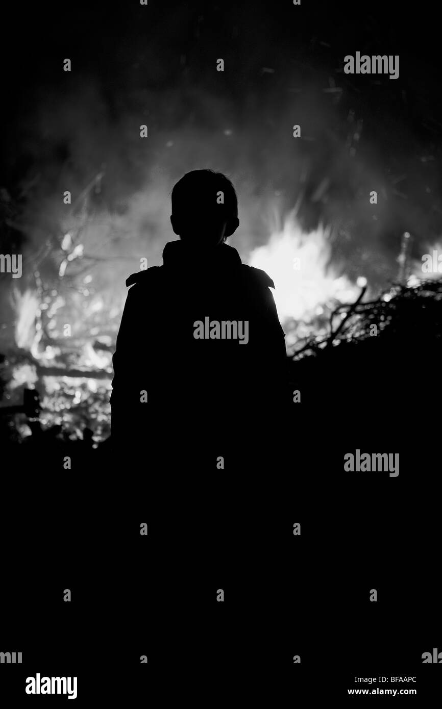 Young boy silhouetted against a fire / bonfire Stock Photo