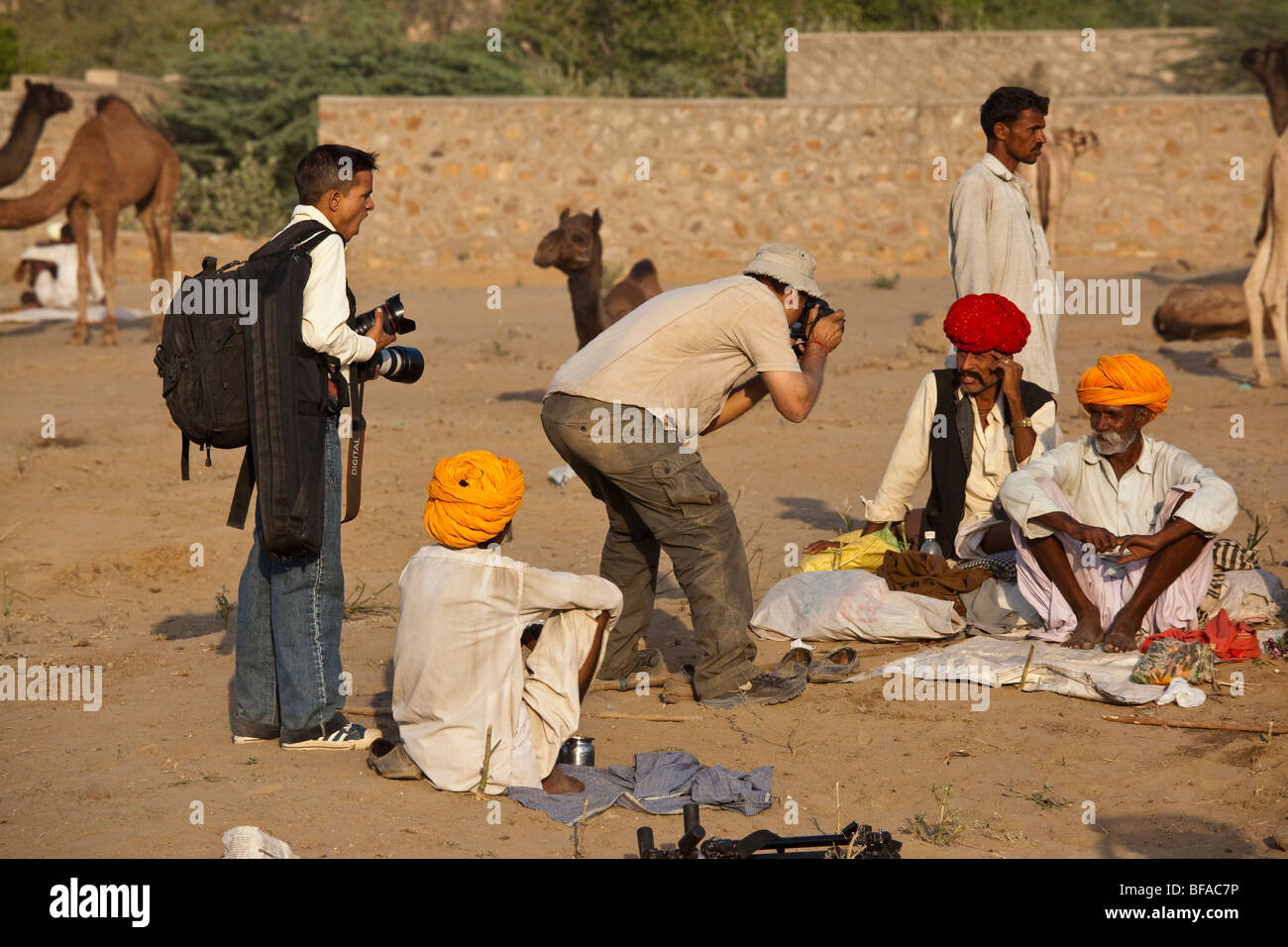 Wealthy Indian man and his yawning helper taking pictures at the Camel Fair in Pushkar India Stock Photo