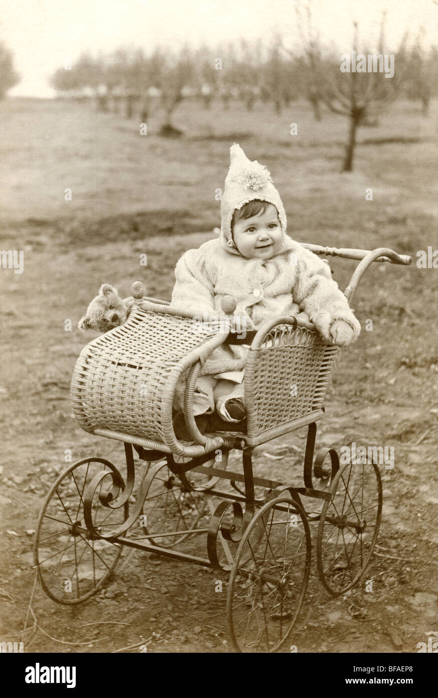 Little Girl & Teddy Bear in Wicker Baby Carriage Stock Photo