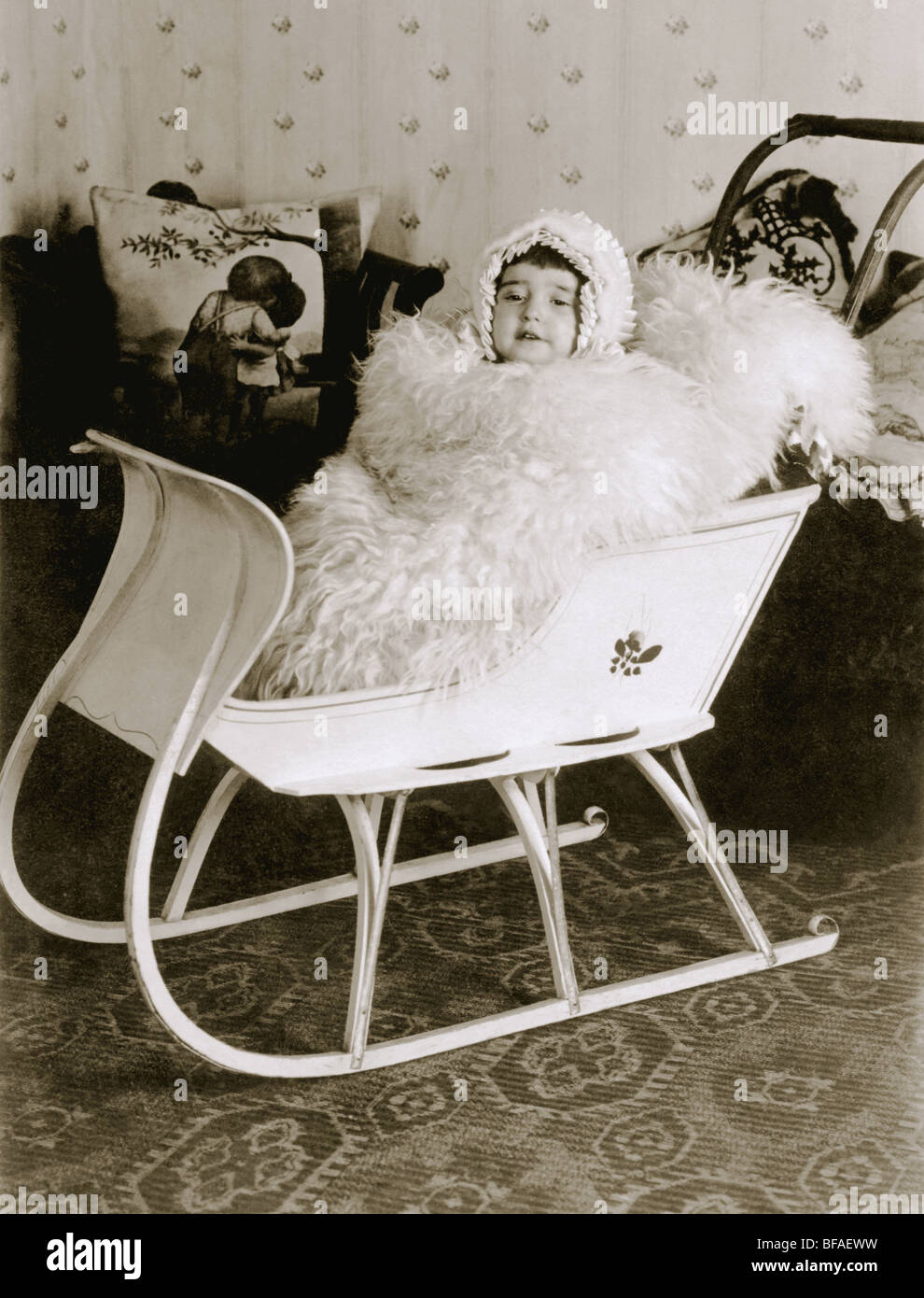 Infant Girl in Sleigh Carriage inside House Stock Photo
