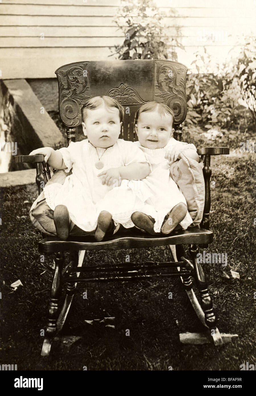Two Infants in Outdoor Rocking Chair Stock Photo