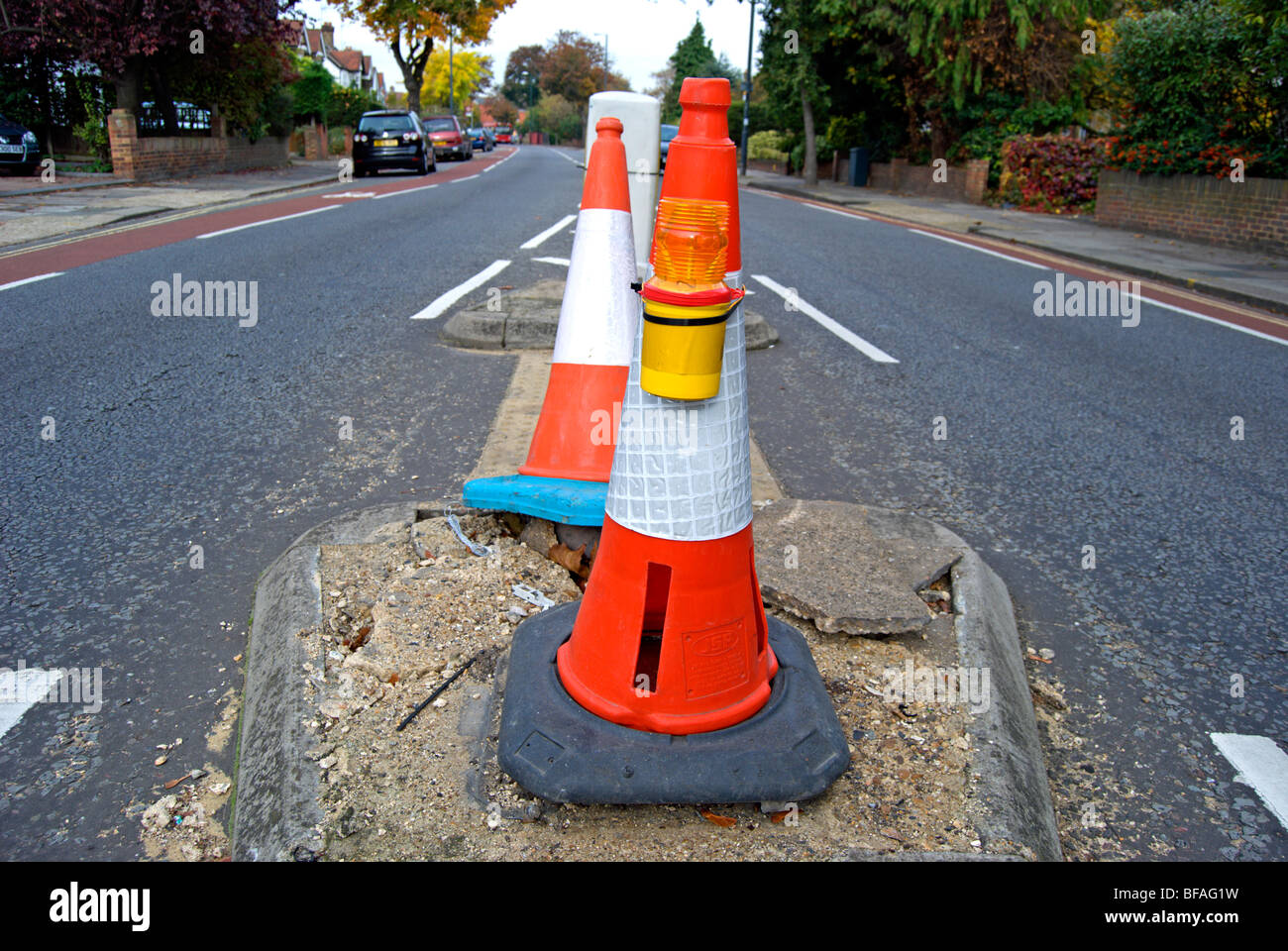 two traffic cones marking a damaged section of road in teddington, middlesex, england Stock Photo