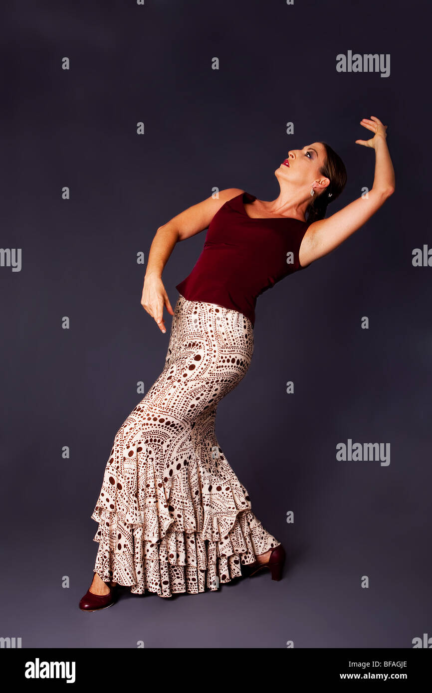 Beautiful female Flamenco dancer doing a typical line pose, wearing modern attire. Spanish woman dancing Flamenco in brown. Stock Photo