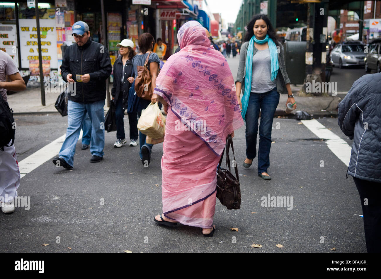 A woman in a sari and head covering crosses the street in the Queens neighborhood of Jackson Heights in New York Stock Photo
