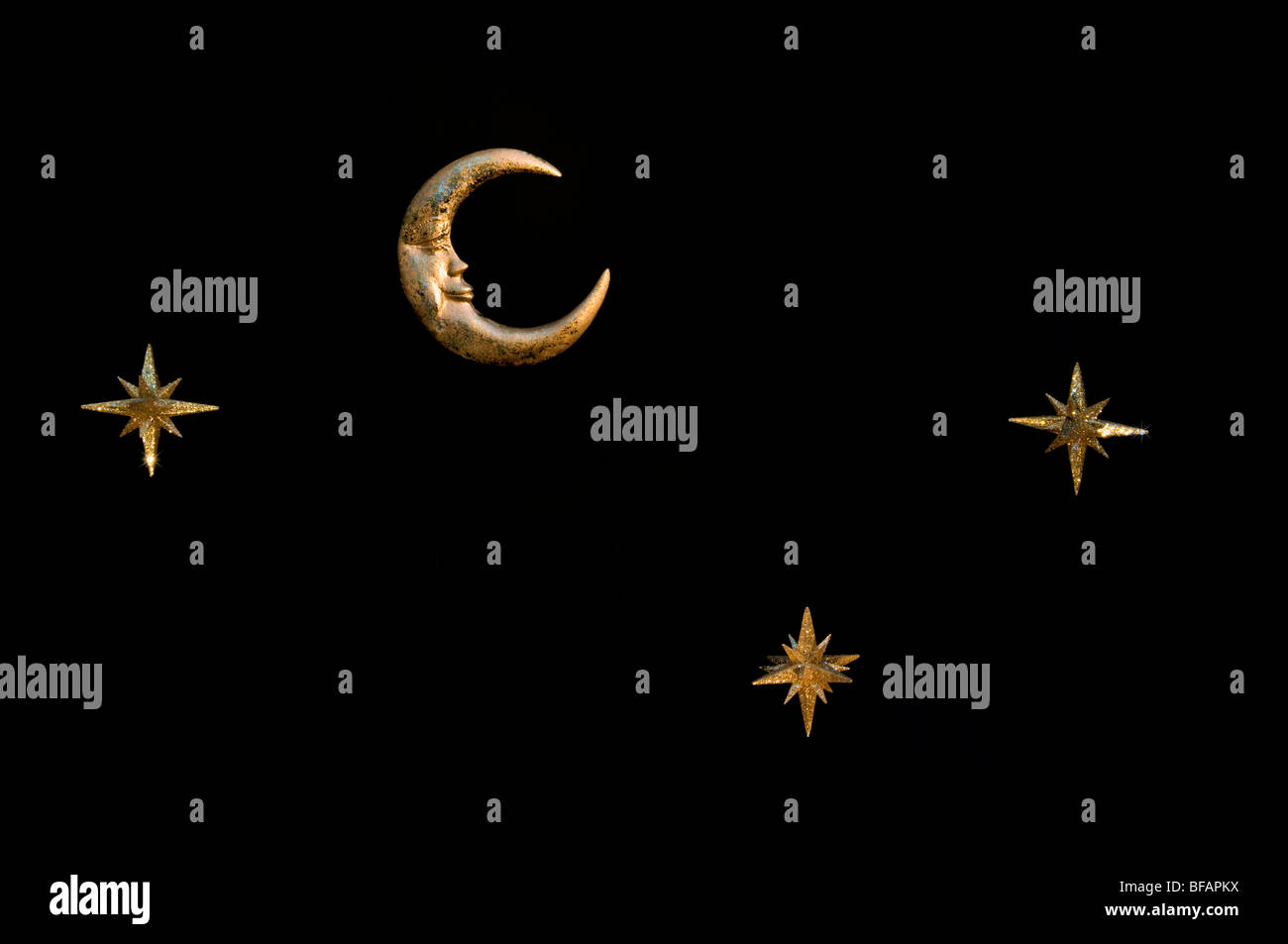 Gold shiny moon and stars sparkly hanging christmas decorations against a black background Stock Photo