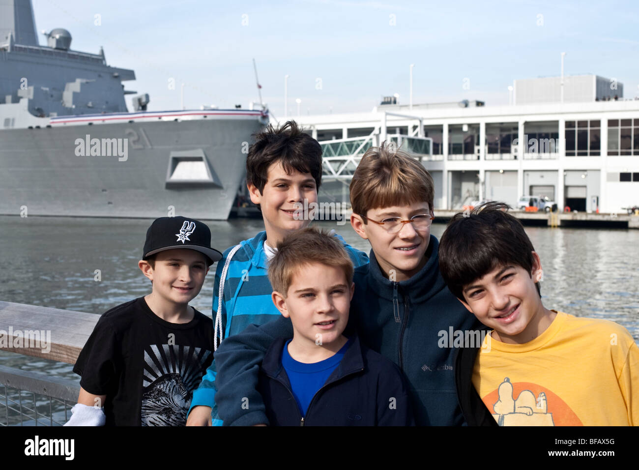 five bright energetic tween boys pose for a portrait with the bow of the USS New York a young  hopeful ship in the background Stock Photo