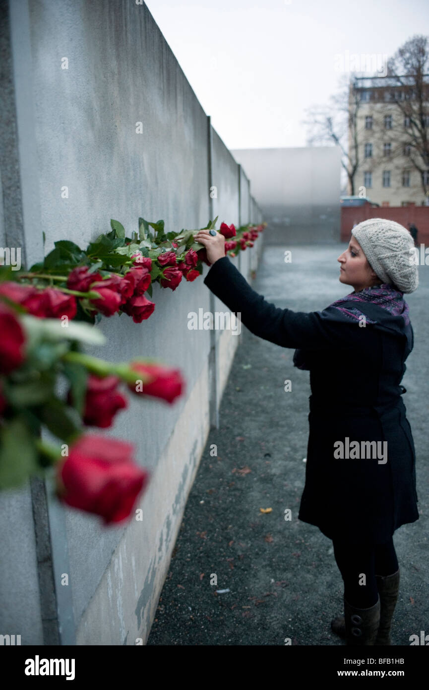 Woman placing red rose in Berlin Wall on 20th anniversary of the fall of the wall to commemorate those who died trying to escape Stock Photo