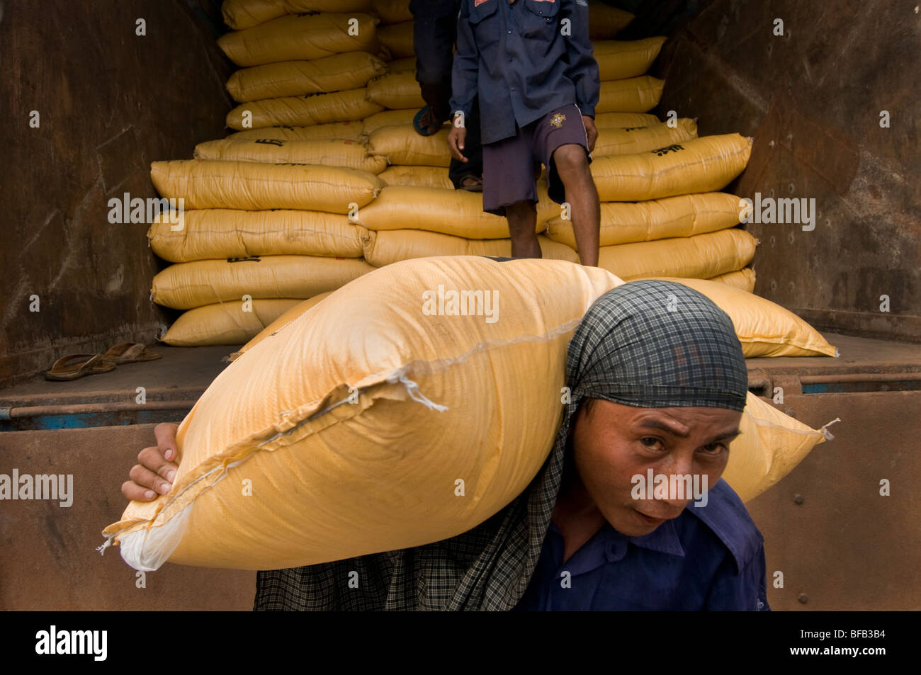 Workers unloading sacks off a truck at the Yangon Jetty in Yangon ...