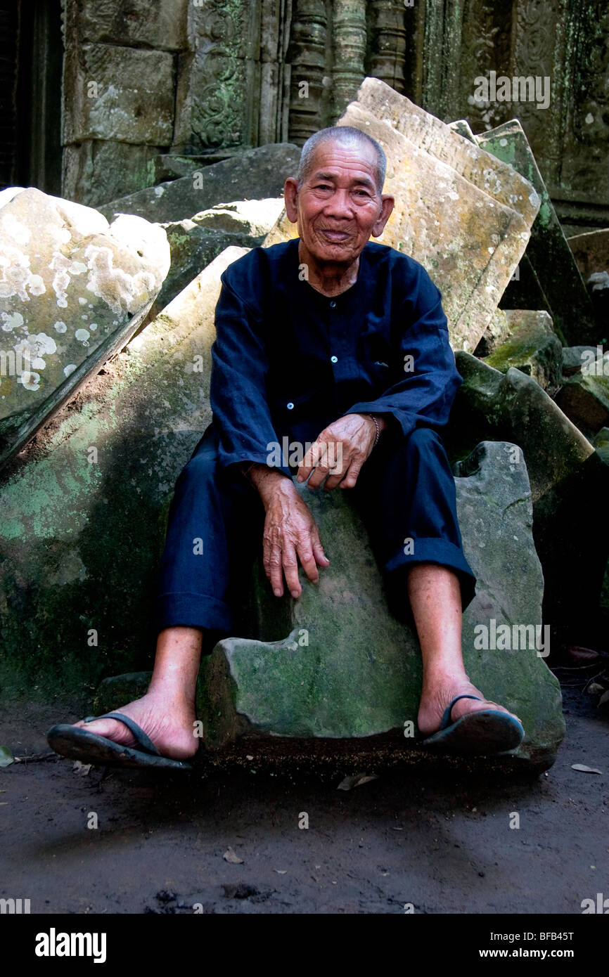 Old man sat on a stone at Ta Prohm, Angkor Wat, Siem Reap, Cambodia Stock Photo