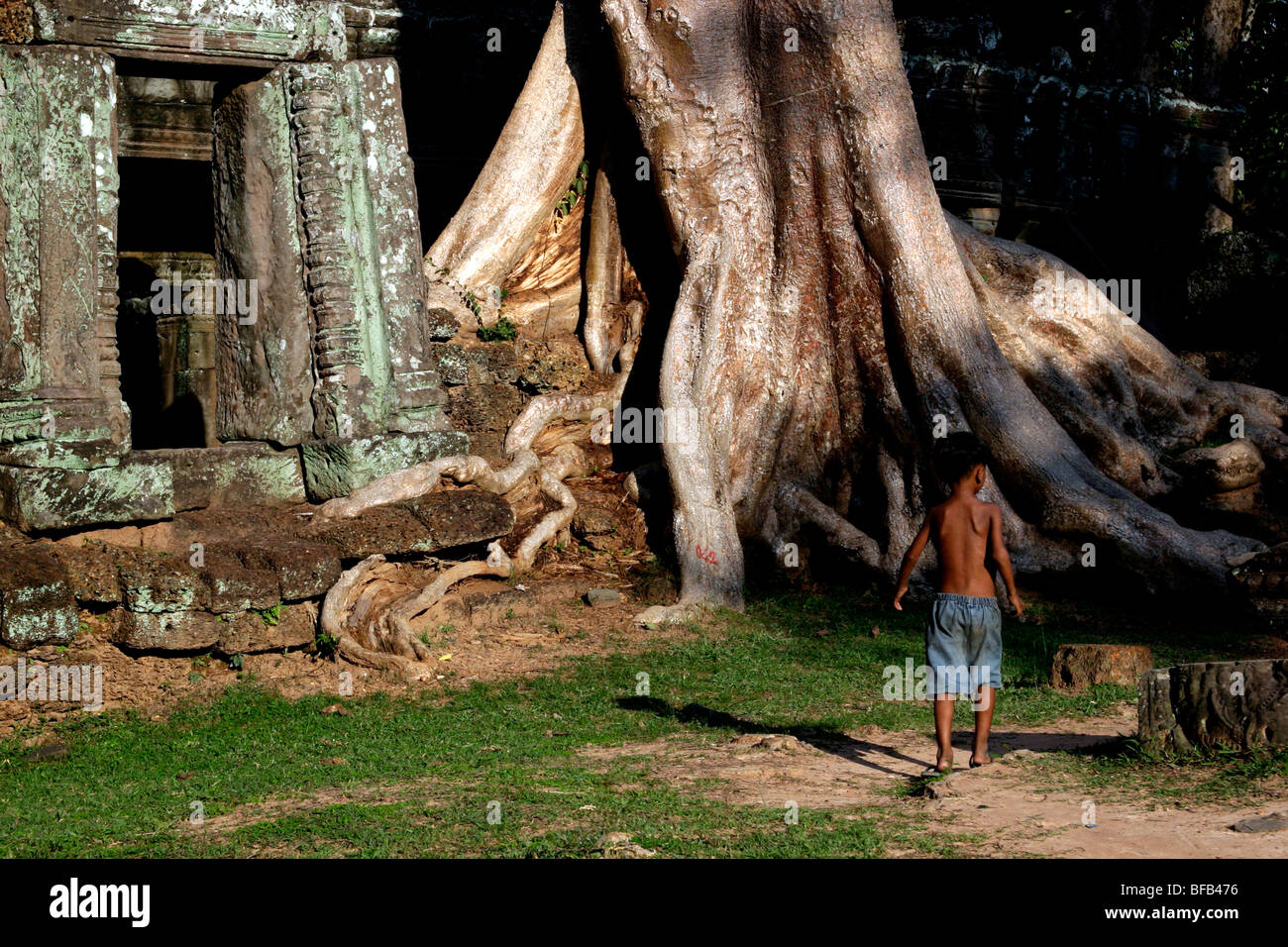 Boy walking past a ruined temple, Angkor Wat, Cambodia Stock Photo
