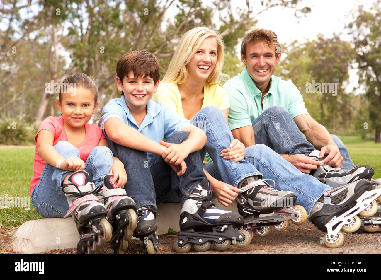 Family Putting On In Line Skates In Park Stock Photo