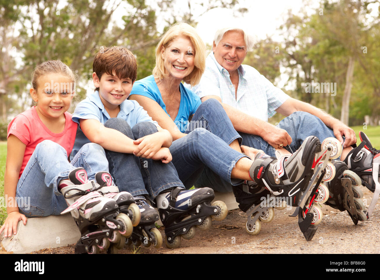 Grandparents And Grandchildren Putting On In Line Skates In Park Stock Photo
