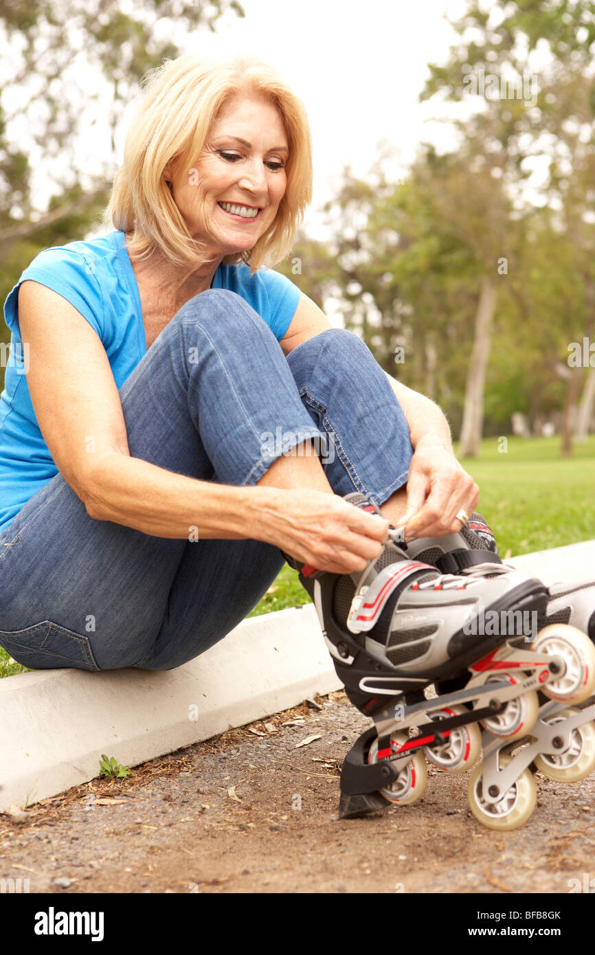 Senior Woman Putting On In Line Skates In Park Stock Photo