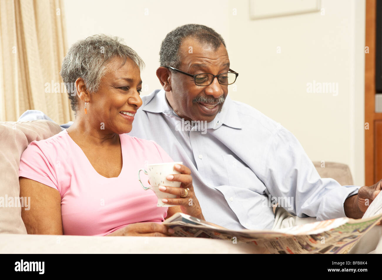 Senior Couple Reading Newspaper At Home Stock Photo