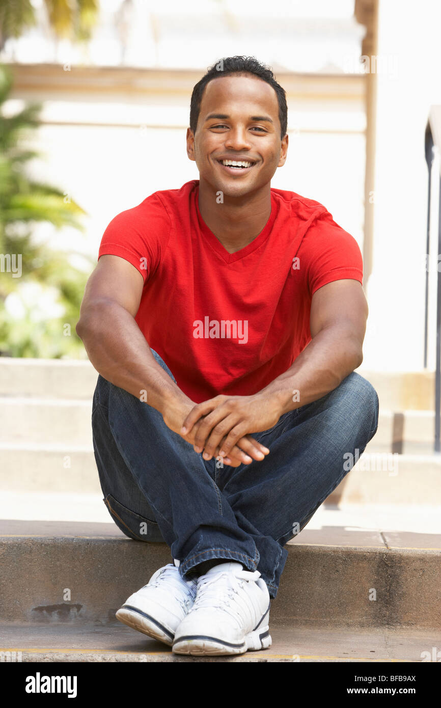 Young Man Sitting On Steps Of Building Stock Photo - Alamy