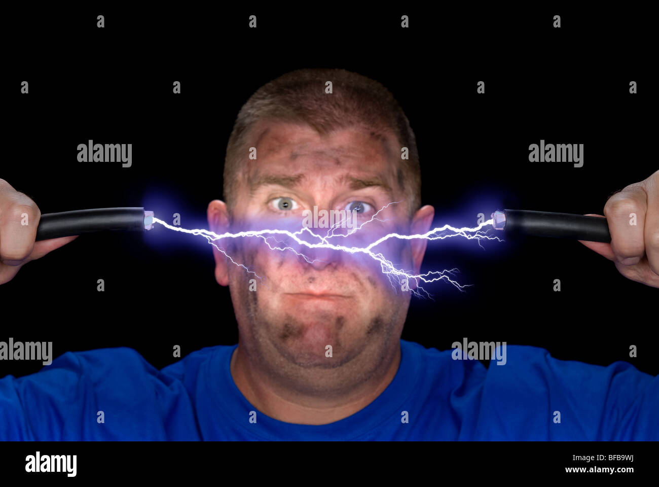 An electrician plays with some live wires, causing an arc of electricity and charring the man's face. Stock Photo