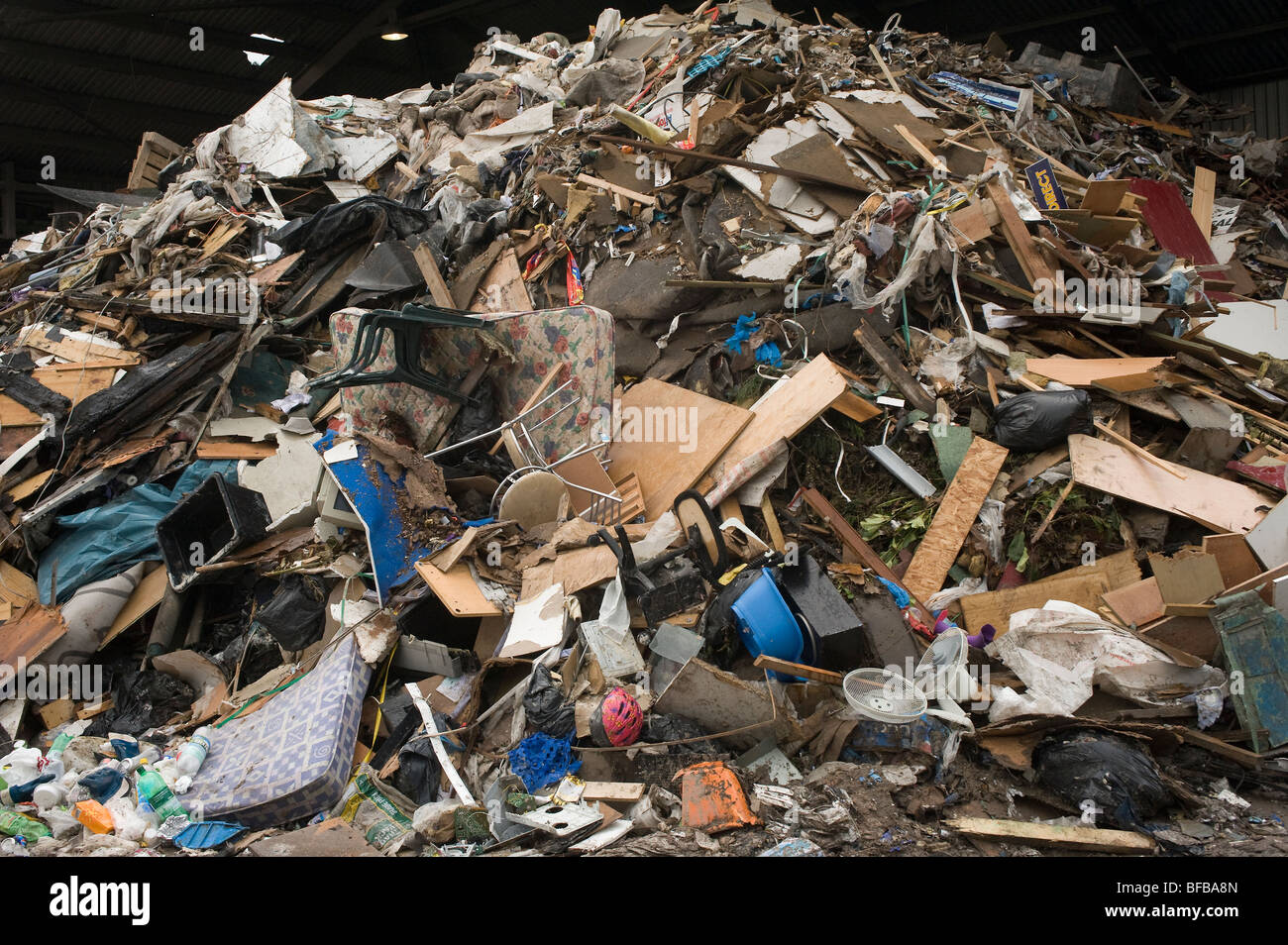 Rubbish piled high at a materials recovery facility waiting to be sorted. Stock Photo