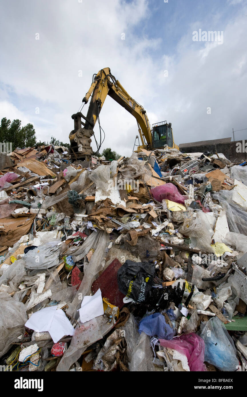 Rubbish piled high at a materials recovery facility being sorted with a
