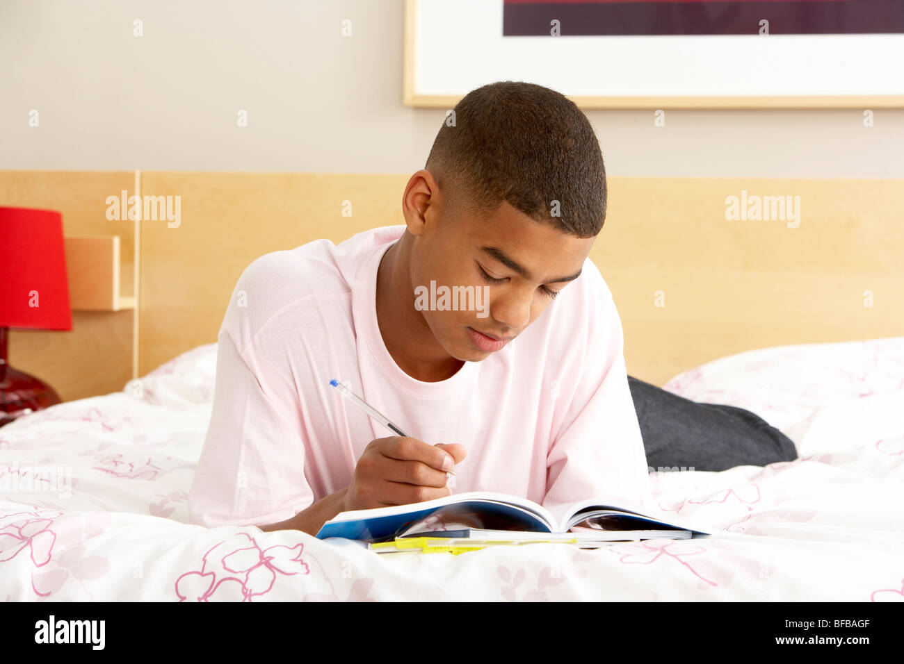 Teenage Boy Writing In Diary In Bedroom Stock Photo