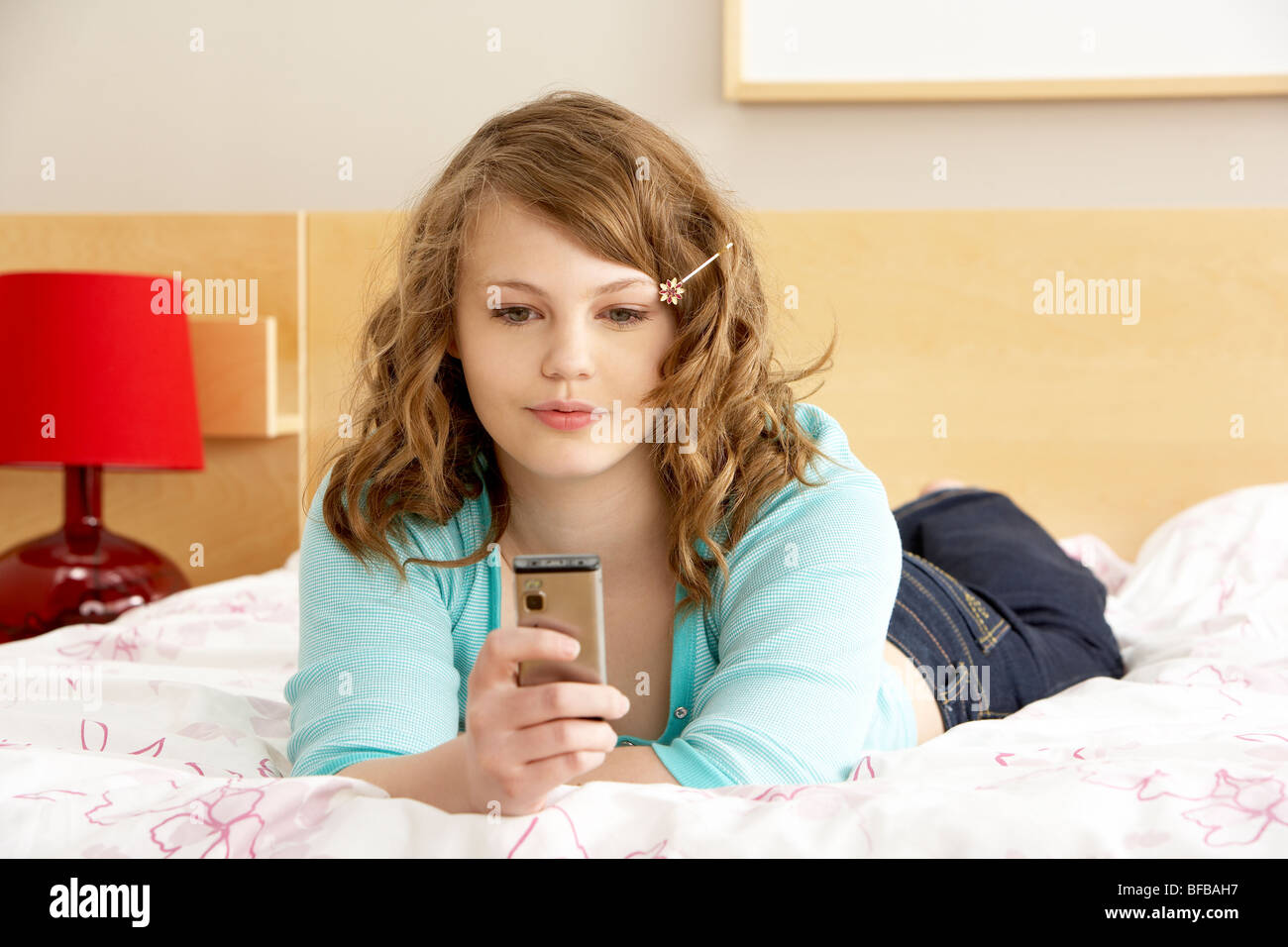 Teenage Girl In Bedroom With Mobile Phone Stock Photo