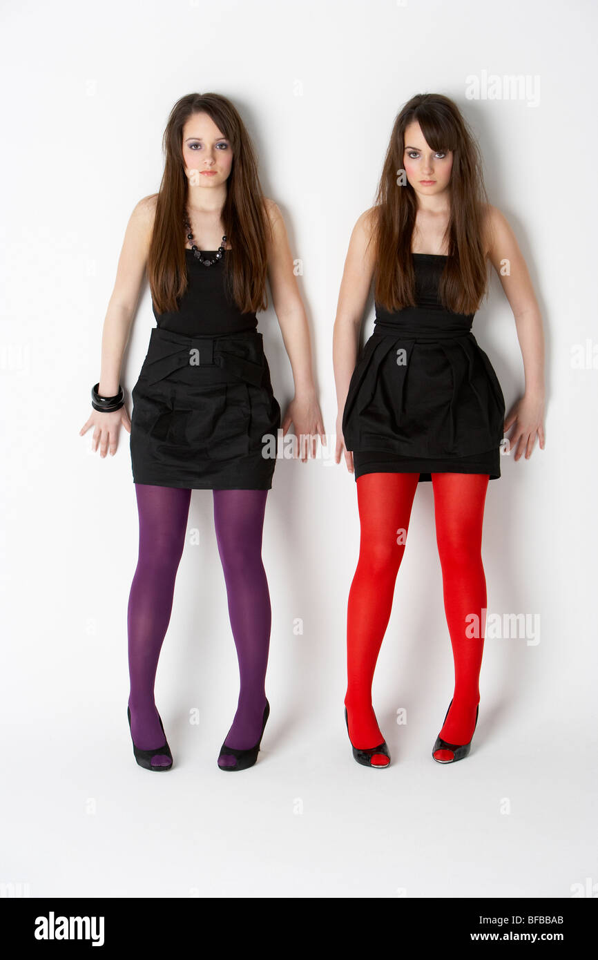 Studio Portrait Of Fashionably Dressed Twin Teenage Girls Stock Photo
