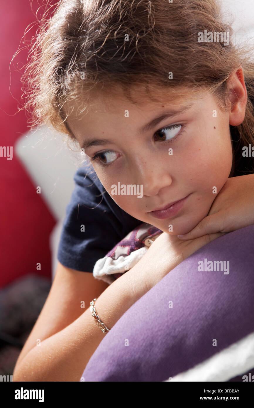 9 years old girl lying on the couch on a bunch of pillow indoors Stock Photo
