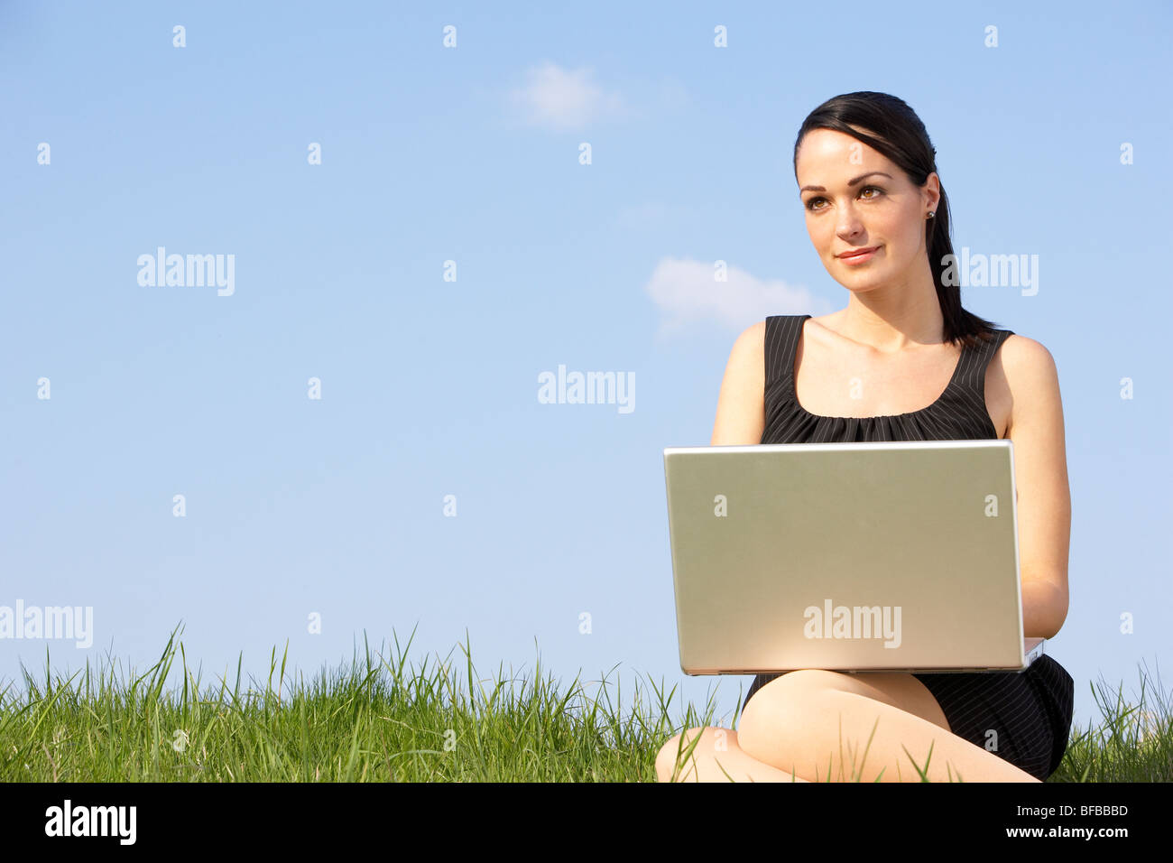 Woman Using Laptop Outdoors In Summer Countryside Stock Photo
