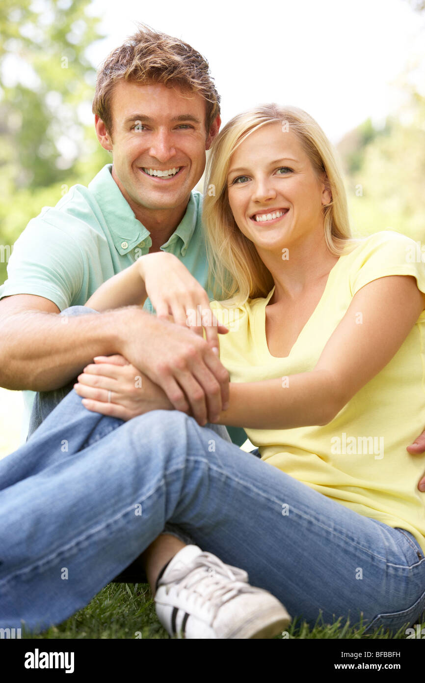 Portrait Of Young Couple Sitting In Park Stock Photo - Alamy