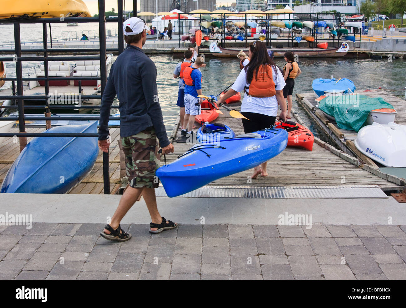 Man and woman carrying a plastic canoe and paddles, Toronto lakeshore