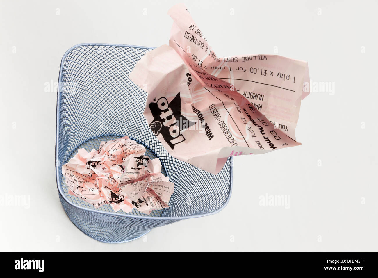 composite image of screwed up unlucky Lotto UK National lottery ticket thrown into a waste paper basket to illustrate wasting money gambling concept Stock Photo