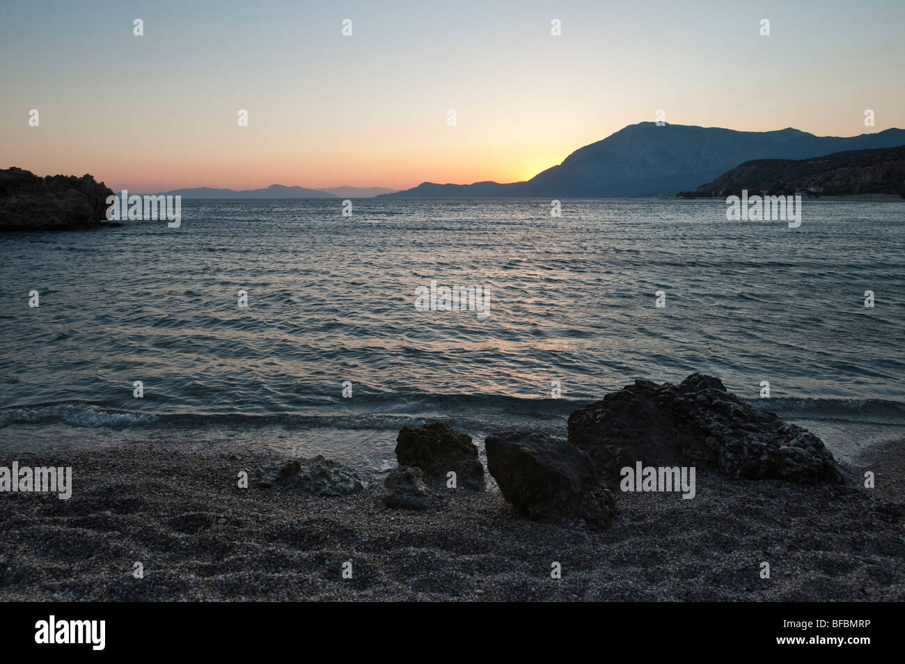 Sunset  behind mountain as seen from a beach on a greek island Stock Photo