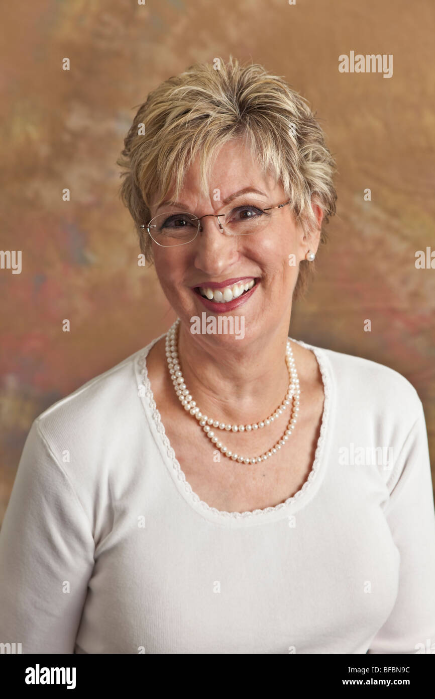 Portrait studio white shirt Happy mature woman in her 60s. MR California Stock Photo