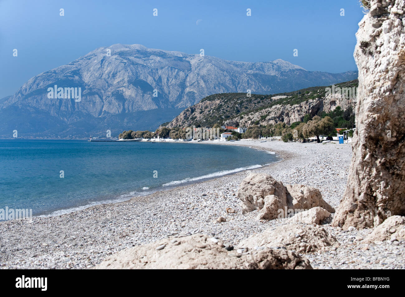 beach on a greek island with rocks and a huge mountain in a distance Stock Photo