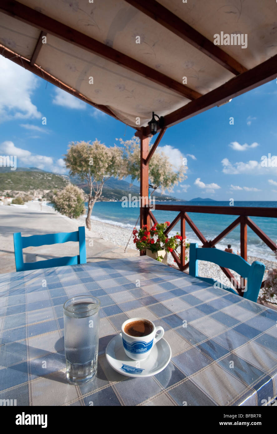 Greek coffee and glas full of water on a table in a tavern on a secluded and serene beach in Greece. Stock Photo
