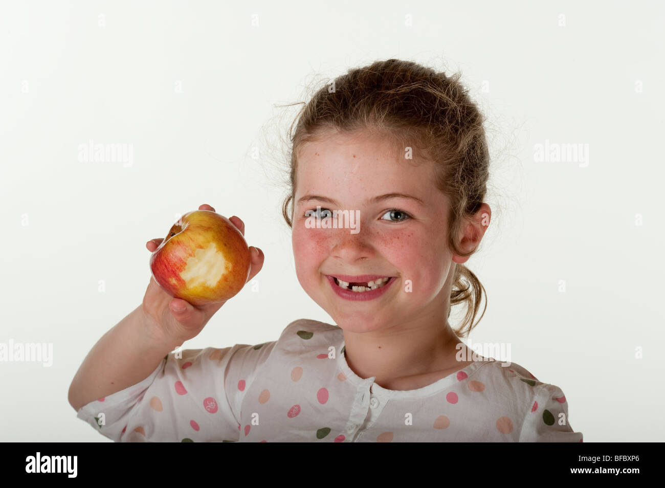 little girl (7 years old) who is missing front teeth eating apple