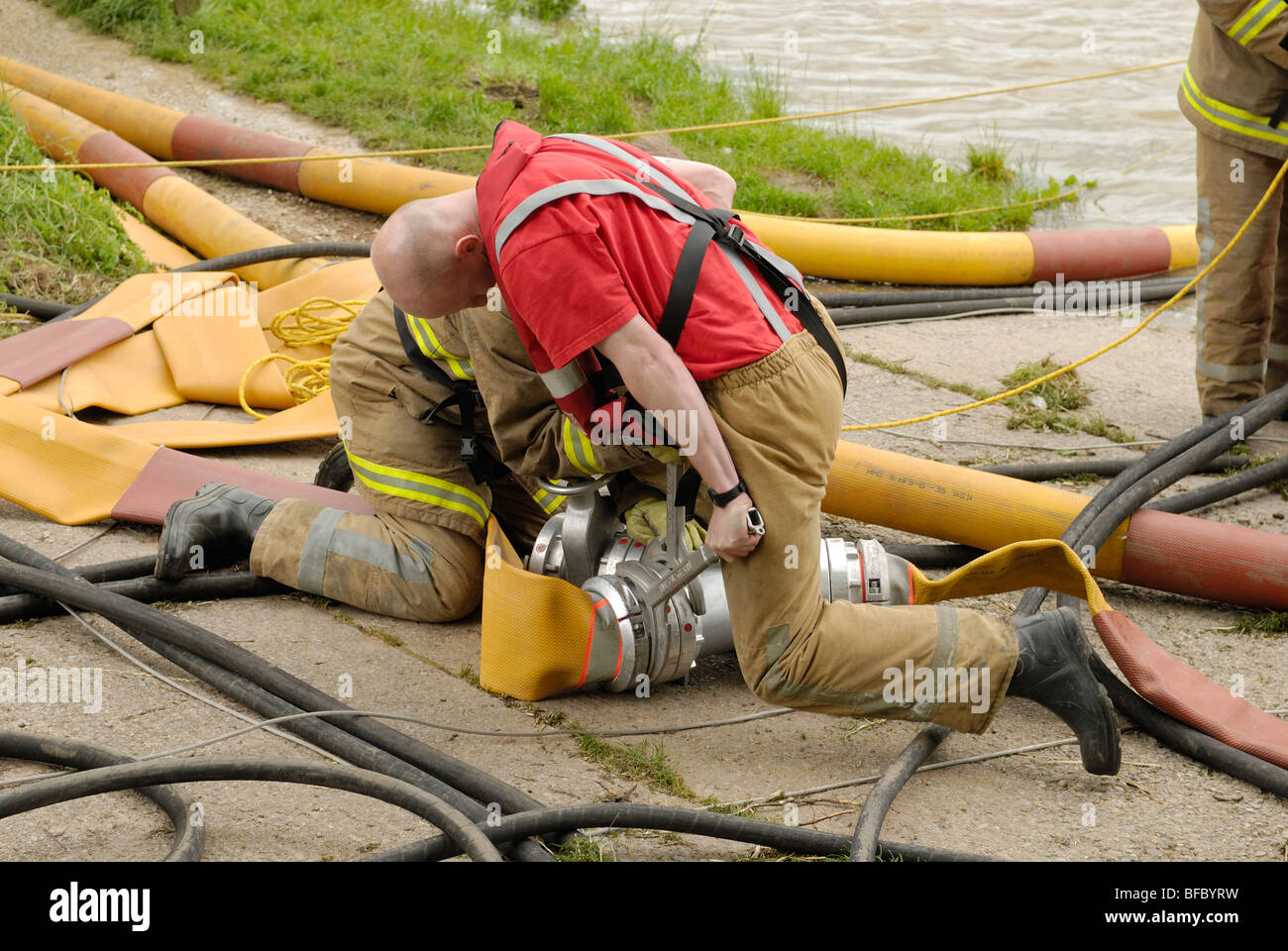 Fire & Rescue Service High Volume pumps and hose used to release flood water build up from behind a weakened and overflowing dam Stock Photo