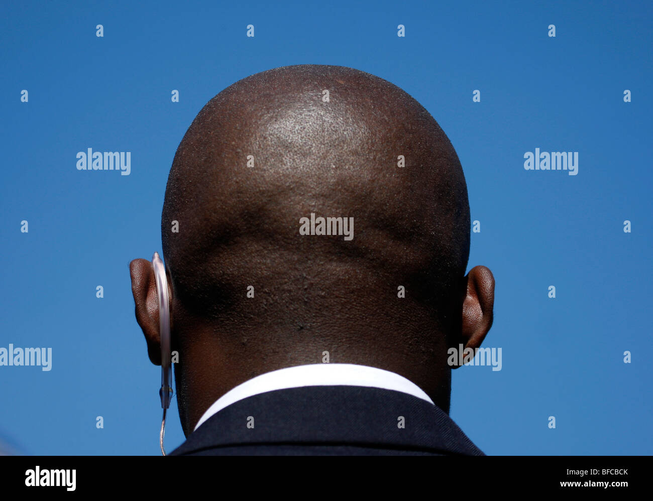 Bald head  of black security guard against blue sky Stock Photo