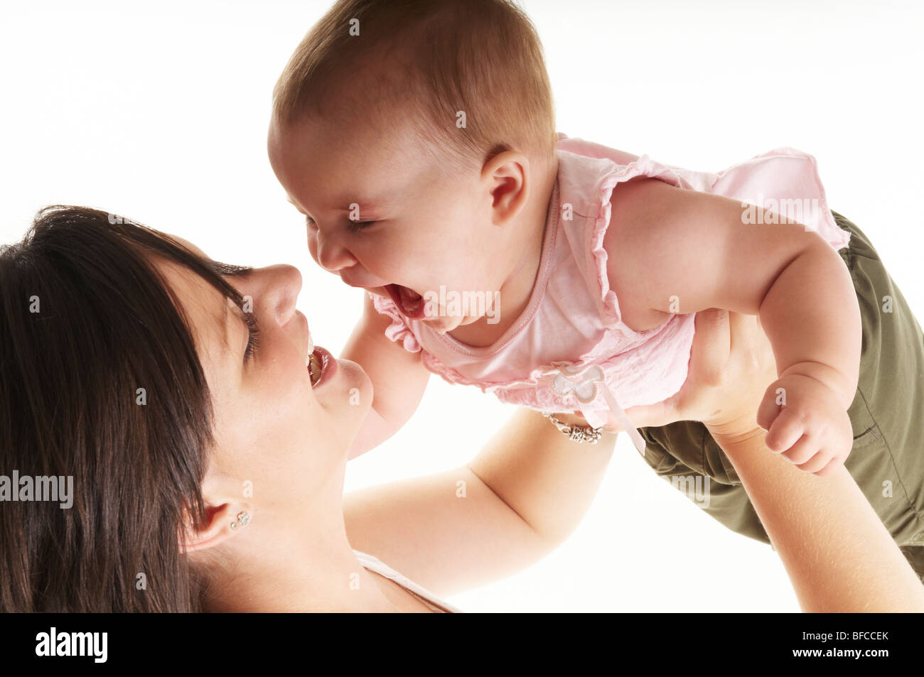 Brunette mum plays with blonde baby daughter on white background. twenty something mum and one year old little girl Stock Photo
