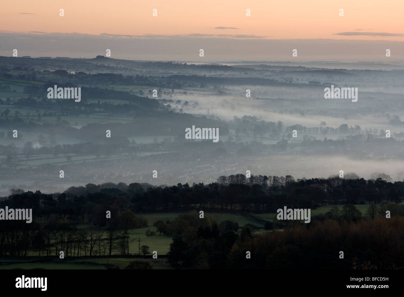 Sunrise, and mist fills the valley of Wharfedale.  A view from Ilkley Moor in West Yorkshire, England towards Almscliff Crag Stock Photo