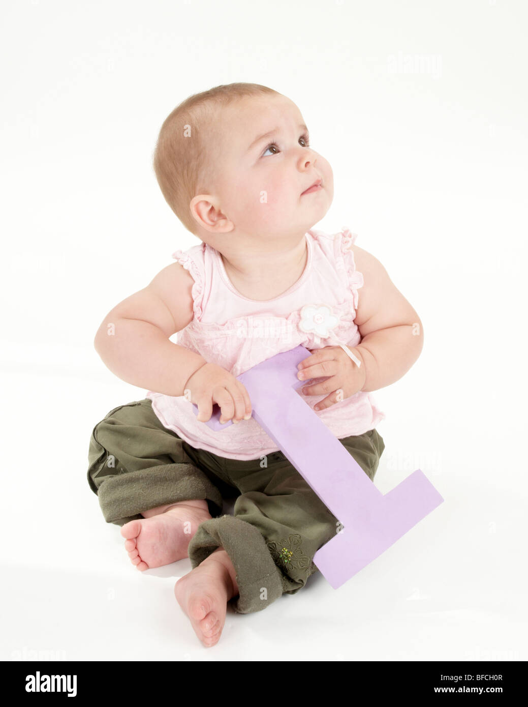 Baby Girl plays with Big Letter in Pink Top and Green Trousers Stock Photo