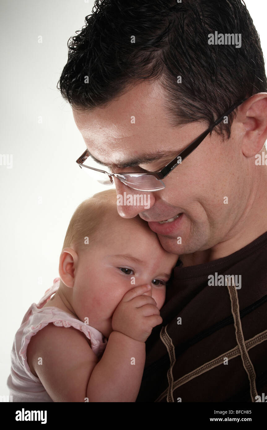 Sleepy little girl tenderly being held by her dad to his chest Stock Photo