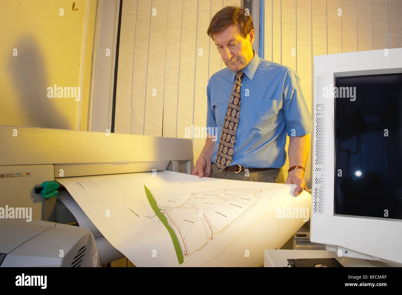 draughtsman with printer plotter of plan and computer monitor in office ...