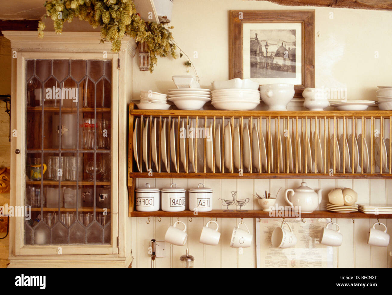 https://c8.alamy.com/comp/BFCNXT/close-up-of-cream-bowls-on-wooden-plate-rack-beside-small-wall-cupboard-BFCNXT.jpg