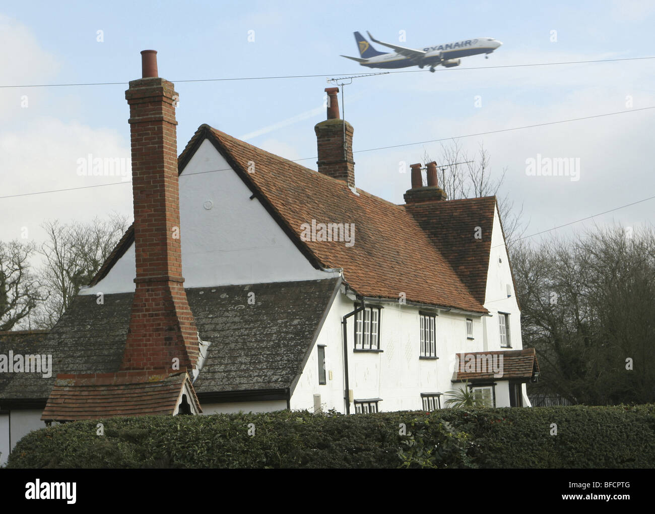 Plane flying over house on approach to Stansted Airport, Essex, UK Stock Photo
