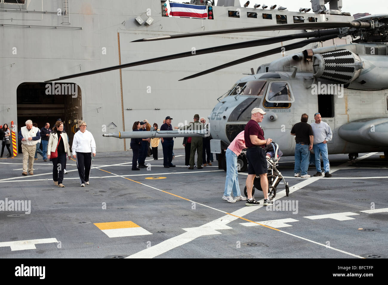 visitors to flight deck USS New York moored at pier 88 New York City gather around fuselage of large lethal Helicopter gunship Stock Photo