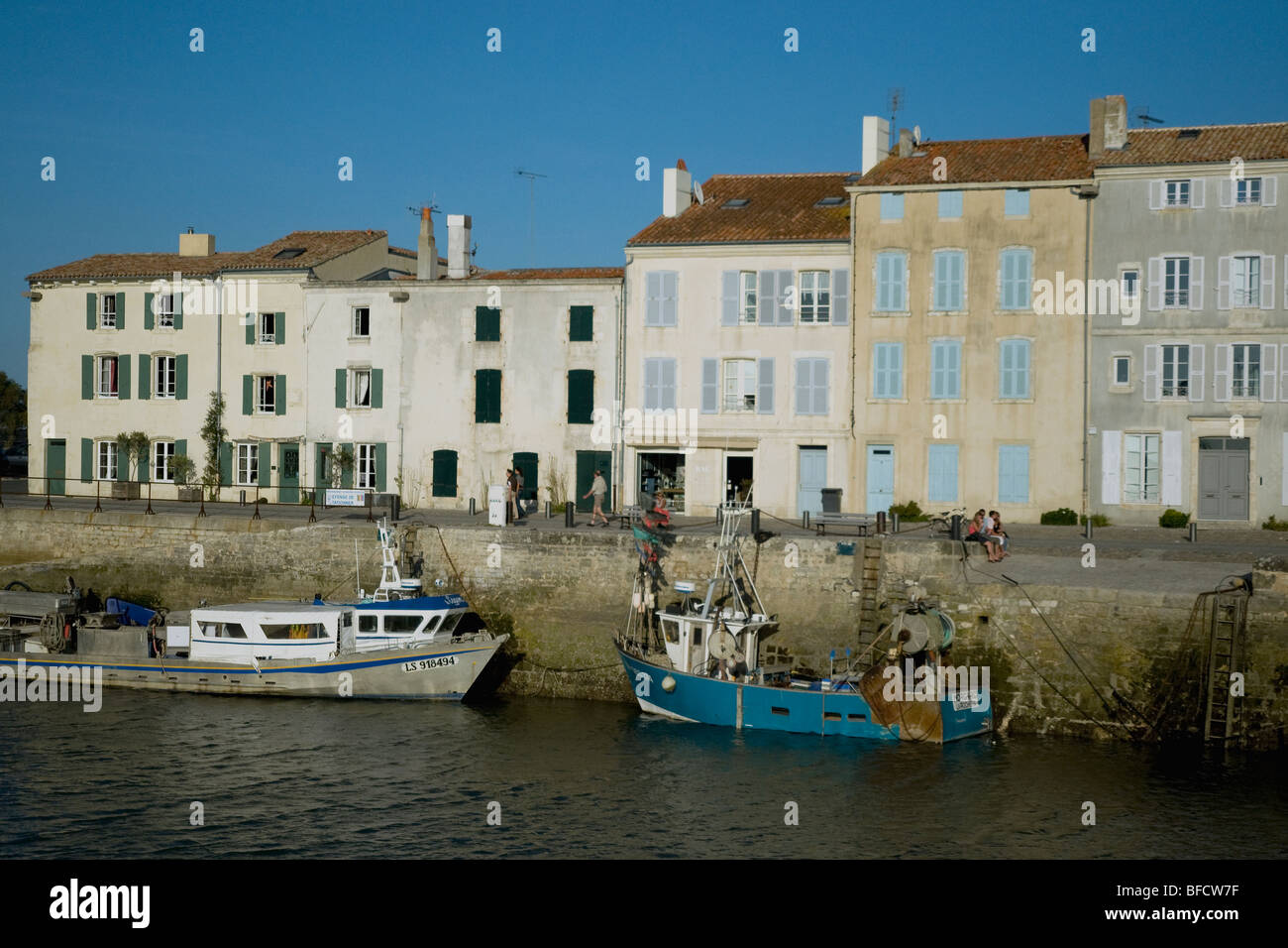 Fishing boats and harbour-side houses in Ile de Ré's popular holiday village of Saint-Martin-de-Ré on France's west coast Stock Photo