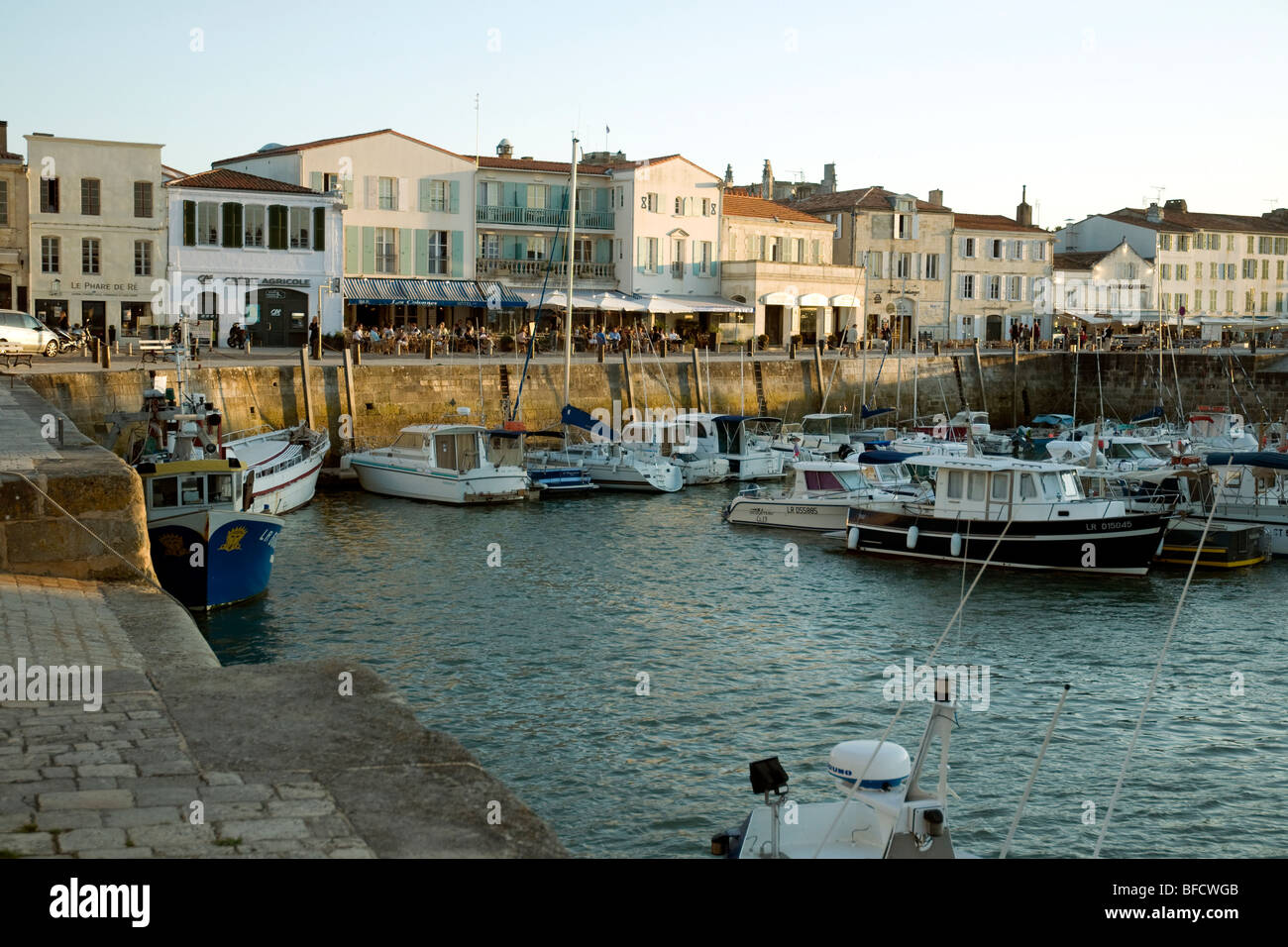 Evening light touches fishing boats, restauran and harbour-side houses in France's popular holiday village of Saint-Martin-de-Ré Stock Photo