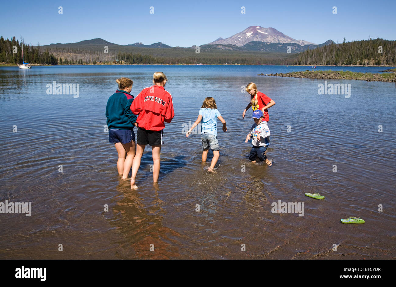 Children on a family outing hunt for crawdads in Elk Lake in the Oregon Cascade Mountains along the Cascade Lakes Highway Stock Photo
