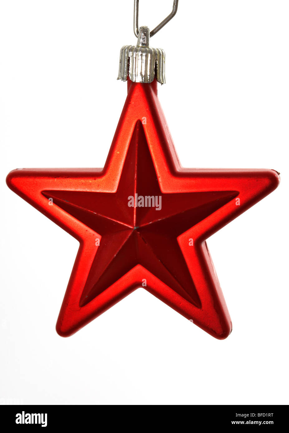 slighty worn red star christmas tree decoration hanging against a white background Stock Photo