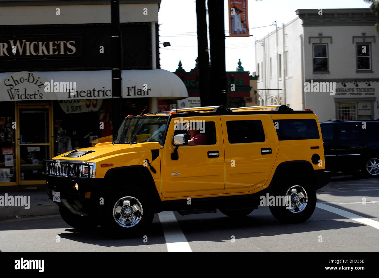 Aggressive driver in a gas guzzler turns the corner in a bright yellow Hummer H2. Stock Photo